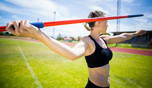 Female athlete about to throw a javelin in the stadium